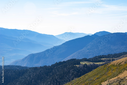 Beautiful landscape in the mountains with peaks against the blue sky and valleys covered with grass