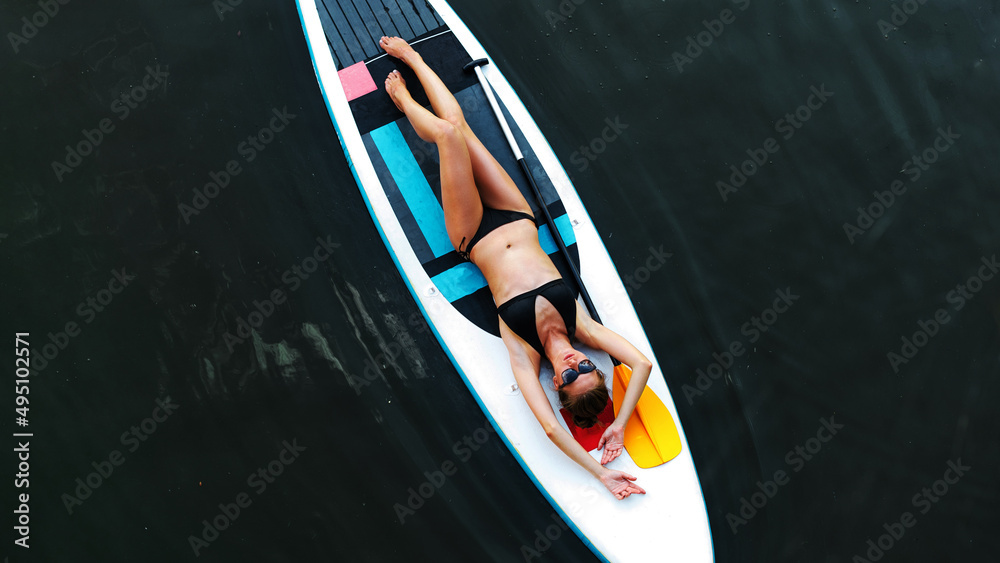 Girl relaxed lying on paddle surf board SUP relaxed in summer