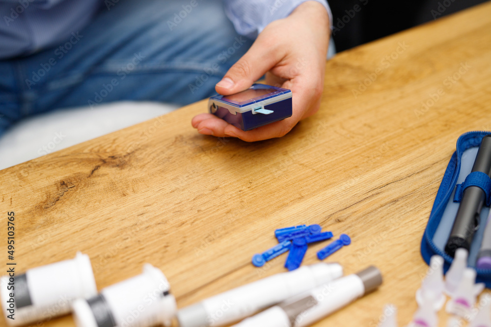 Close up photo of man hand sitting at the table and holding glucose meter for checking blood sugar level, diabetes monitor concept. Close up photo of man hand sitting at the table and holding glucose meter for checking blood sugar level, diabetes monitor concept.