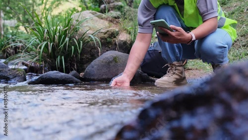 Environmental engineers inspect water quality at natural water sources and record data on smartphones. Woman scientist and environmental issues. World environment day concept.