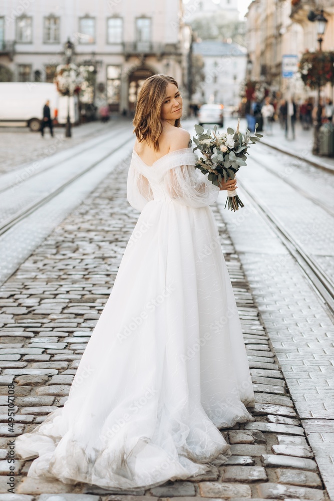 Beautiful bride with a bouquet posing in the city streets Beautiful bride with a bouquet posing in the city streets