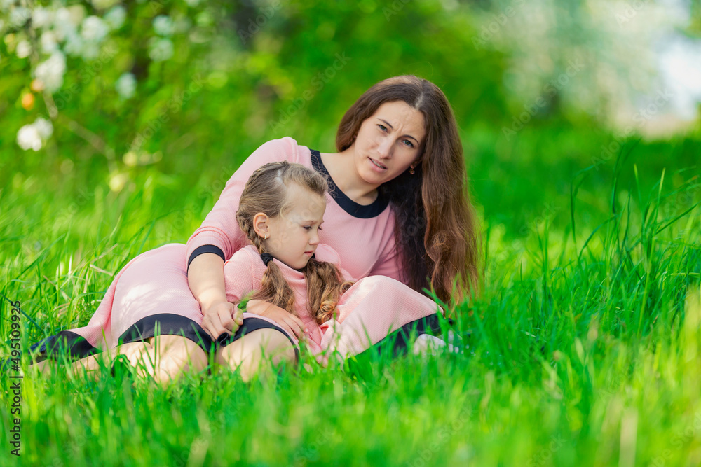 mother and daughter in identical dresses lie in the grass mother and daughter in identical dresses lie in the grass