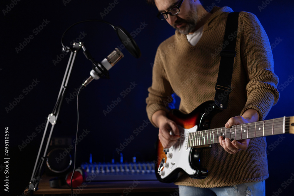 Obraz premium Man singing and playing guitar. Musician in record studio holding acoustic guitar