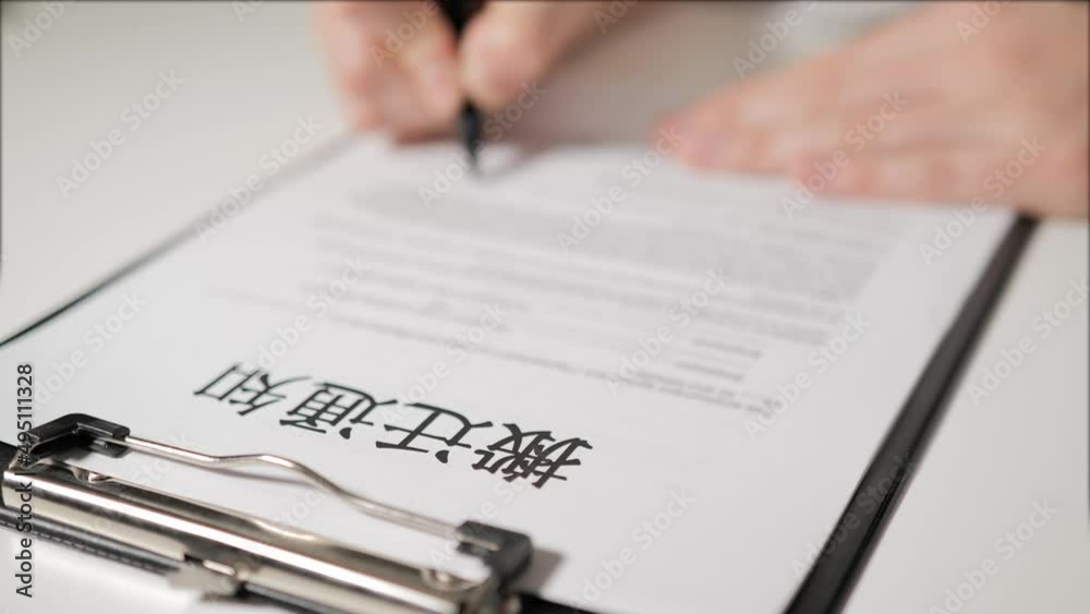 eviction notice in Chinese-speaking language. A person's hand signs a document. A warning. He is deprived of property, a mortgage on a mortgage. eviction notice in Chinese-speaking language. A person's hand signs a document. A warning. He is deprived of property, a mortgage on a mortgage.