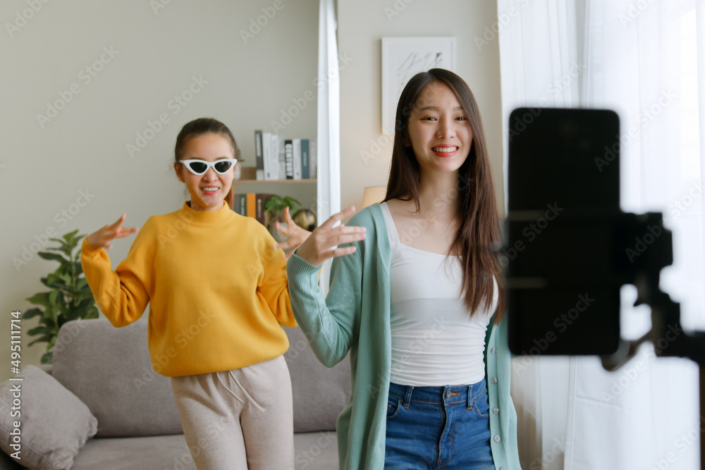 Asian young woman with her friend created her dancing video by smartphone camera together. To share video on tiktok social media application Asian young woman with her friend created her dancing video by smartphone camera together. To share video on tiktok social media application