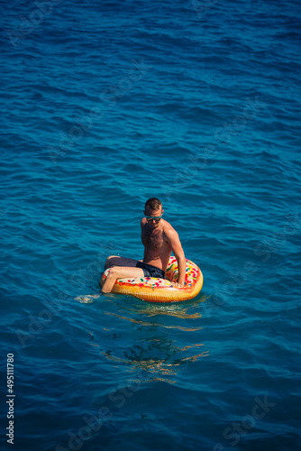 A man floats on an inflatable ring in the sea with blue water. Vacation at the sea on a sunny day. Turkey vacation concept. Selective focus © Дмитрий Ткачук