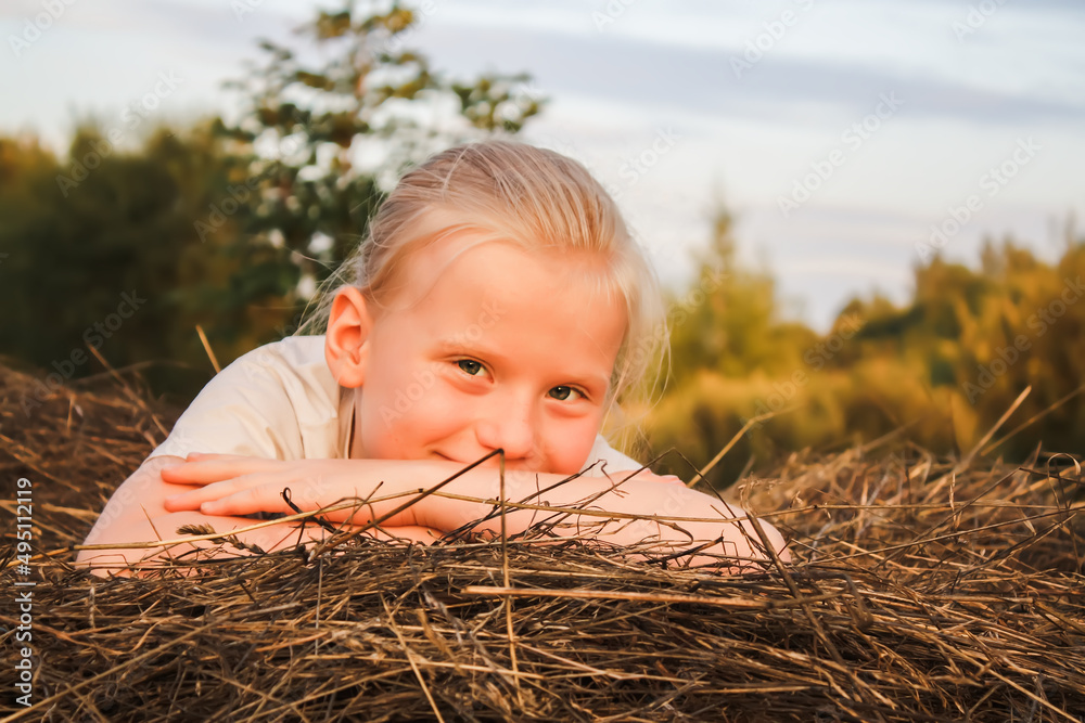 A happy little girl having a good time in the countryside. Child on a haystack. A happy little girl having a good time in the countryside. Child on a haystack.
