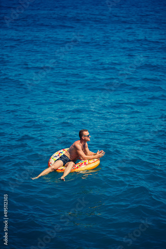 A man floats on an inflatable ring in the sea with blue water. Vacation at the sea on a sunny day. Turkey vacation concept