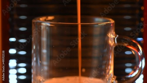 Macro shot of automatic coffee machine or coffee maker pouring espresso into a glass cup. Close up with limited depth of field