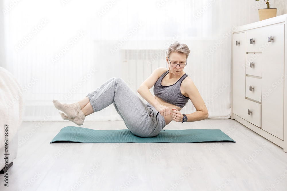 adult woman in sportswear shakes her abs doing at home