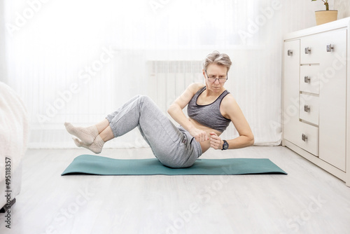 adult woman in sportswear shakes her abs doing at home
