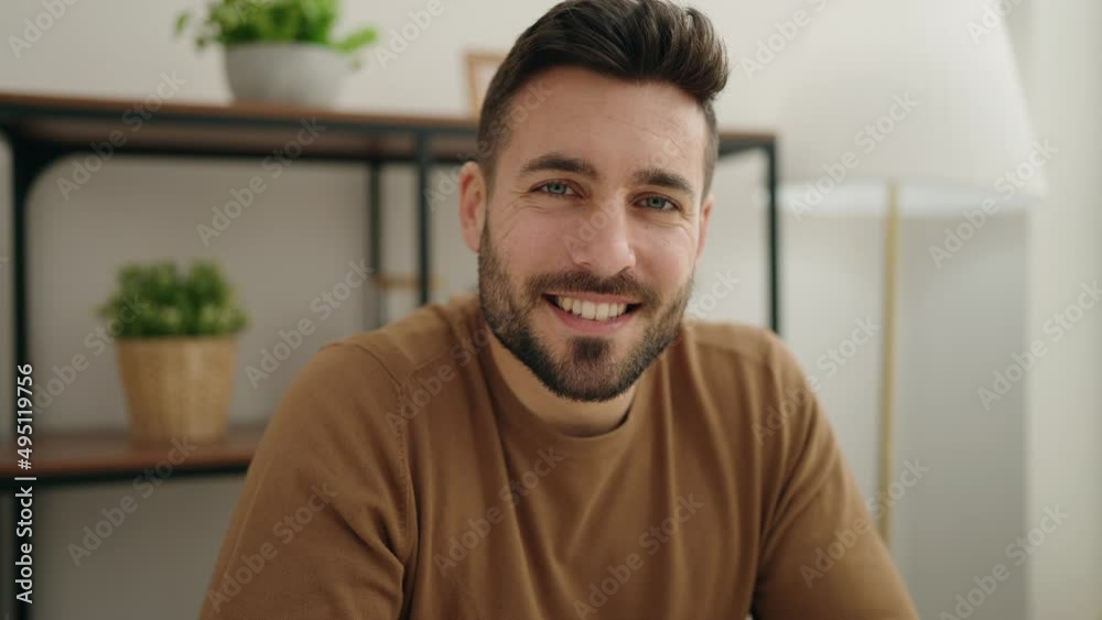 Young hispanic man smiling confident sitting on table at home Young hispanic man smiling confident sitting on table at home