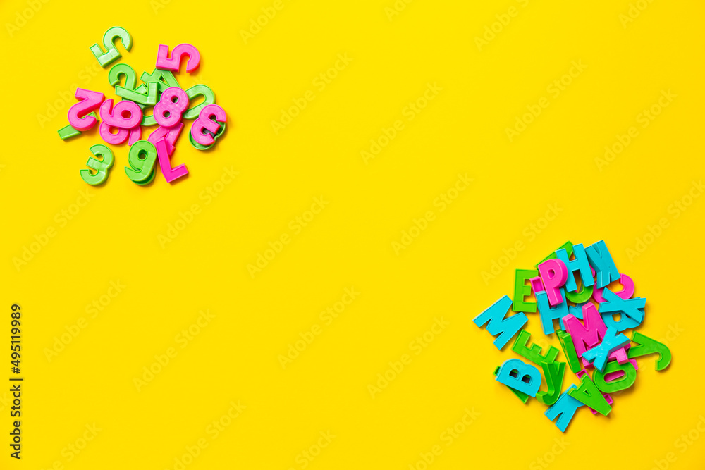 The English letters and numbers 1 2 3 4 5 6 7 8 in the heap. Copy space. Colorful plastic alphabet isolated on yellow background. Math distance education banner. Online language course. Studying game