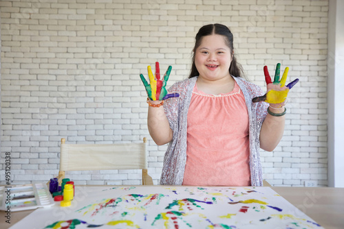 down syndrome teenage girl showing painted hands, drawing a picture on paper photo
