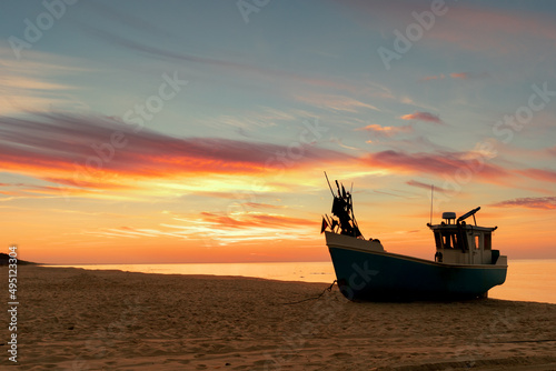 Fishing boat standing on beach during beautiful sunset at seashore © leszekglasner