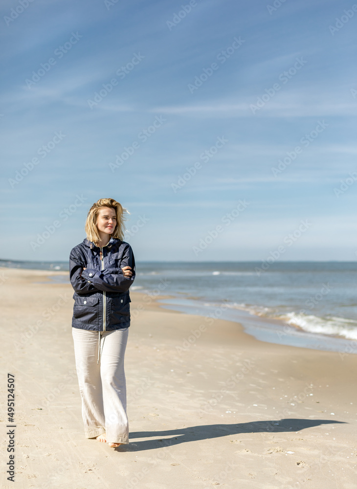 Young pretty woman at windy day walking on beach
