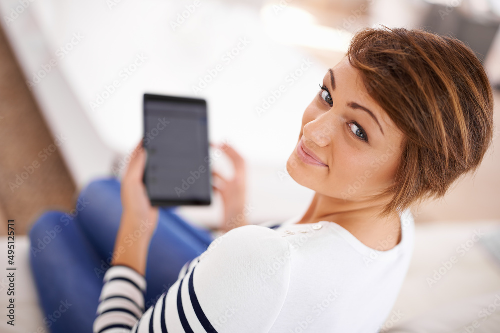 Dont even think about seperating me from my tablet. Shot of a beautiful young woman reading her tablet while relaxing at home. Dont even think about seperating me from my tablet. Shot of a beautiful young woman reading her tablet while relaxing at home.