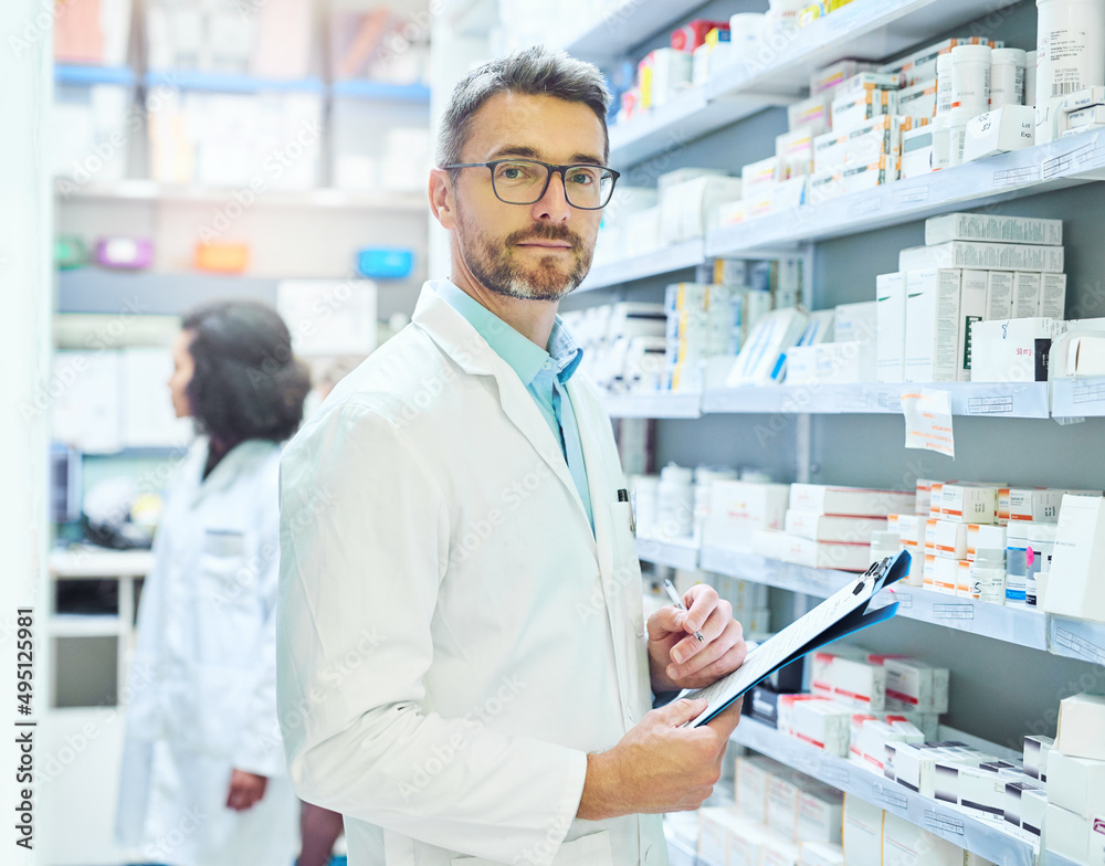 Medication is my expertise. Shot of a mature man doing inventory in a pharmacy with his colleague in the background.