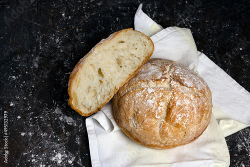 Fresh homemade crisp bread with flour on black wooden table. Healthy baked bread on the fabric over dark backdrop. Traditional bakery rustic style concept.