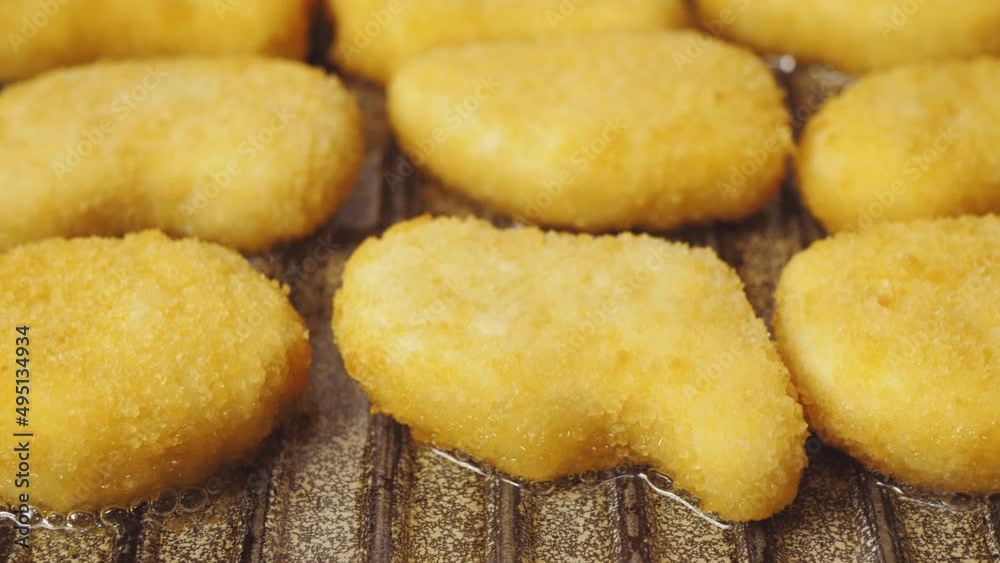Breaded chicken nuggets are fried in a pan in oil. Close-up Breaded chicken nuggets are fried in a pan in oil. Close-up