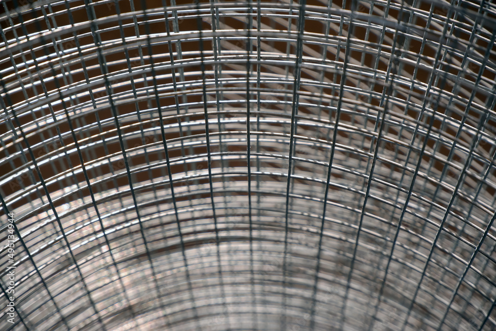 Construction grid with a square cell rolled into a roll. Close-up selective focus. A roll of mesh wire made of steel.