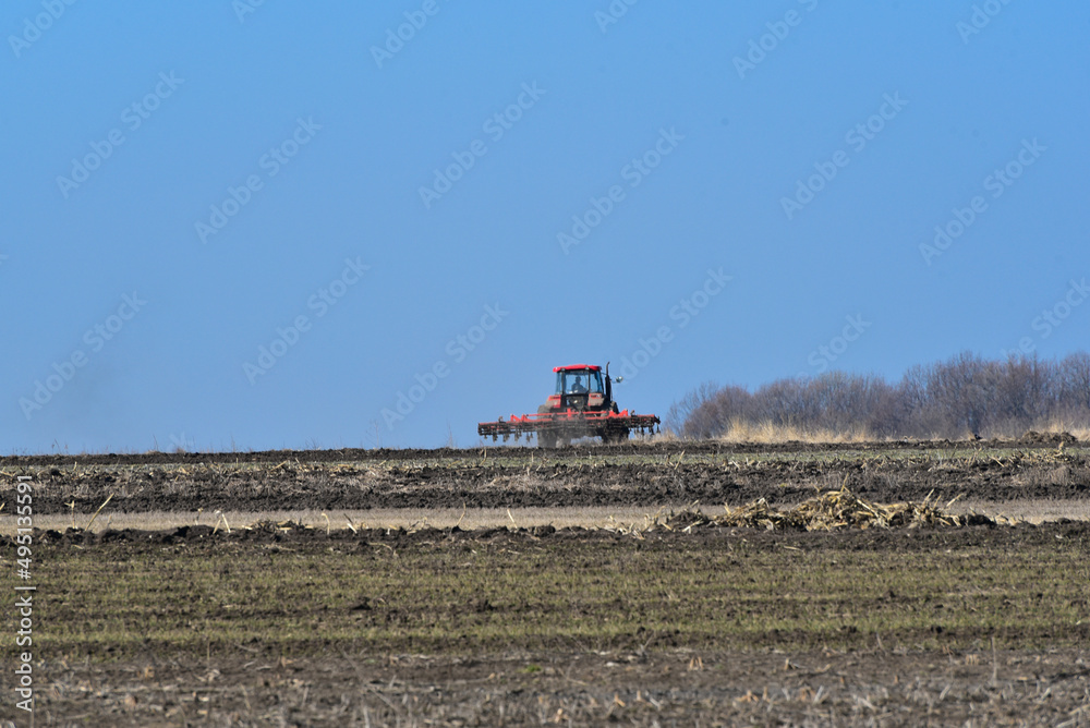 Tractor plowing the soil in spring closing the moisture, preparing the land for sowing. Agriculture concept photo Tractor plowing the soil in spring closing the moisture, preparing the land for sowing. Agriculture concept photo