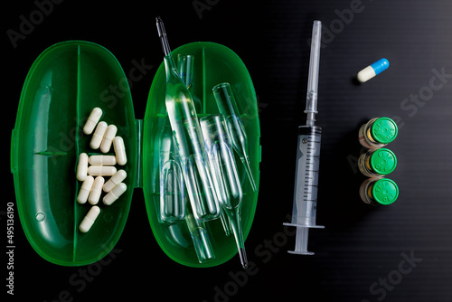 Slika na platnu Medical accessories, syringe, pills, capsules, ampoules, black background