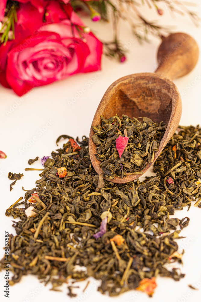 Fototapeta premium Heap of Dry green tea, white tea leaves with herbs in a wooden spoon on white background.
