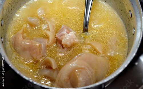 Selective focus of an Arabic Egyptian cuisine of kawareh soup ( trotters soup ) , cooked cow feet in a cooking pot with onion, cow boneless trotters with its soup photo