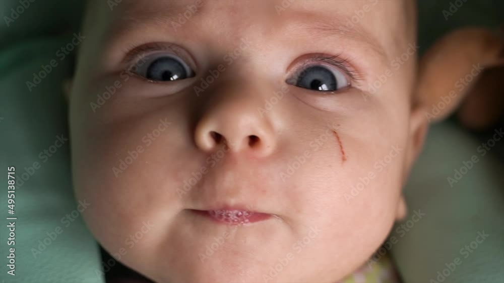Close-up of a child's face. Perky, cheerful, baby with big cheeks, looks at the camera, big, blue eyes and indulges, twitches with pleasure Close-up of a child's face. Perky, cheerful, baby with big cheeks, looks at the camera, big, blue eyes and indulges, twitches with pleasure