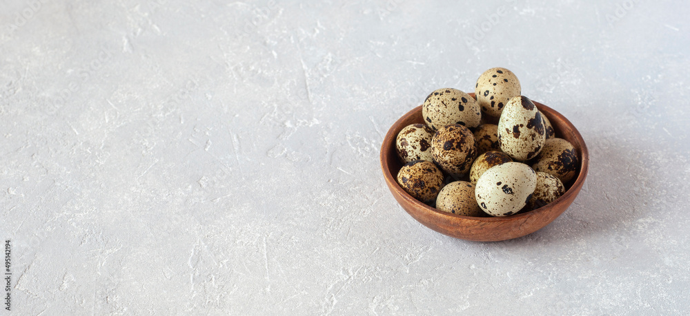 Quail eggs in wooden bowl on grey concrete background Quail eggs in wooden bowl on grey concrete background