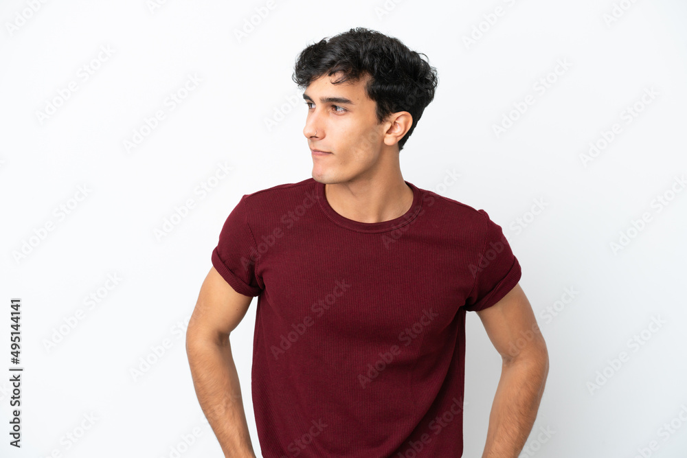 Young Argentinian man isolated on white background having doubts while looking side Young Argentinian man isolated on white background having doubts while looking side