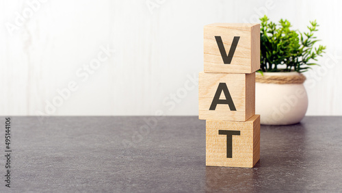 letters of the alphabet of VAT on wooden cubes, green plant, white background photo