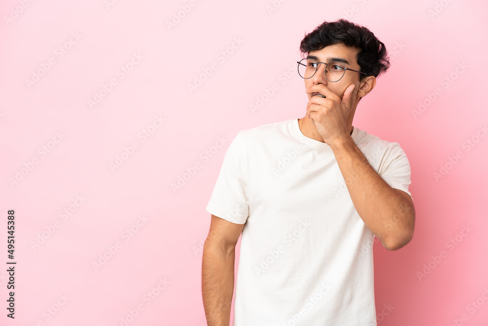 Young Argentinian man isolated on pink background doing surprise gesture while looking to the side Young Argentinian man isolated on pink background doing surprise gesture while looking to the side