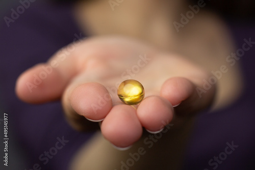 Obraz na płótnie Closeup of a woman holding a fish oil capsule – source of vitamin D and omega 3 fatty acids. w salonie