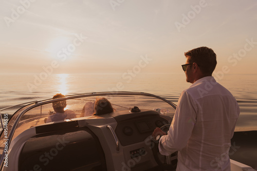 A senior couple in casual outfits with their son enjoy while riding a boat at sea at sunset. The concept of a happy family. Selective focus  © .shock