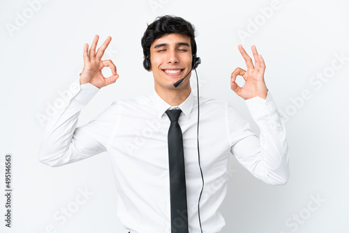 Telemarketer man working with a headset isolated on white background in zen pose