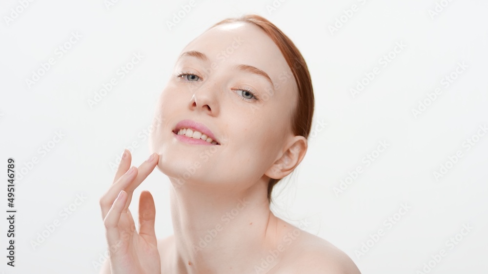 Close-up beauty portrait of young redhead Caucasianwoman touches her face on white background | Face care products commercial