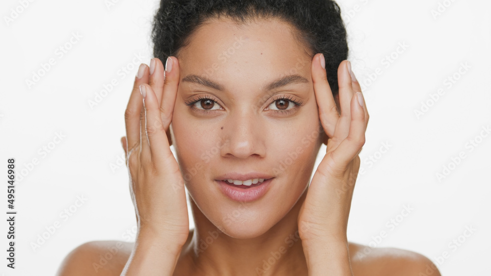 Big close-up beauty portrait of young African American woman lifts skin around her eyes with fingers on white background | Eye bags removal concept Big close-up beauty portrait of young African American woman lifts skin around her eyes with fingers on white background | Eye bags removal concept