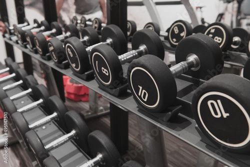Closeup of kilogram dumbbells placed on a dumbbell rack at the gym. Weight training equipment.