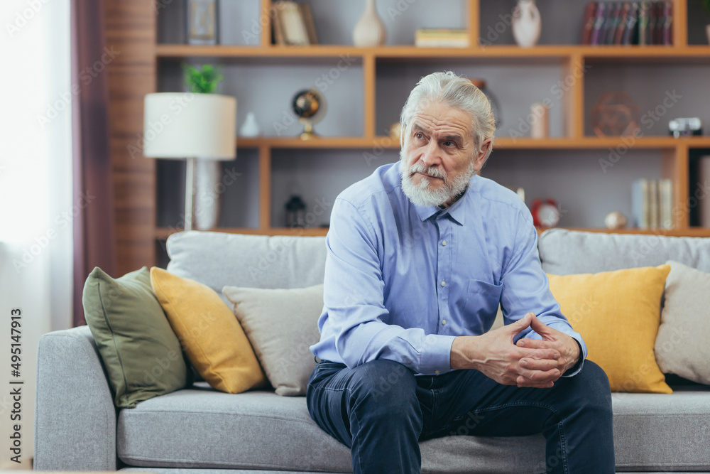 Serious for pensive grandfather man sitting on sofa at home