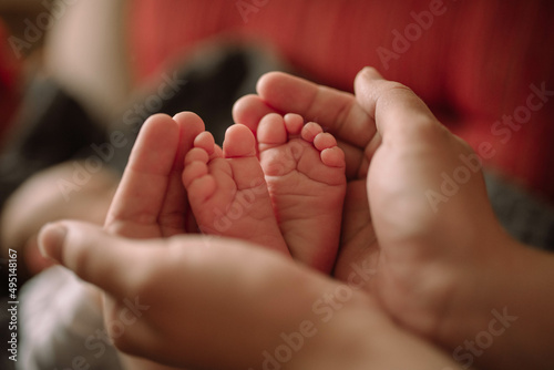 Small legs of a newborn baby in mom's hands