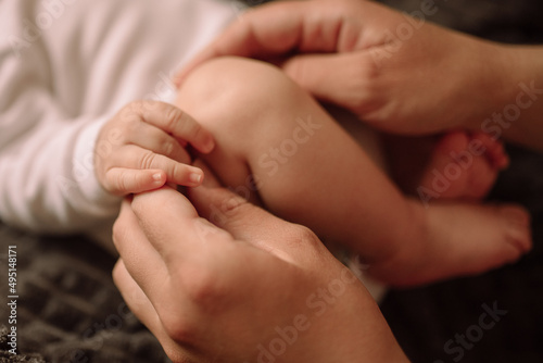 Legs and arms of a newborn and mother's hands