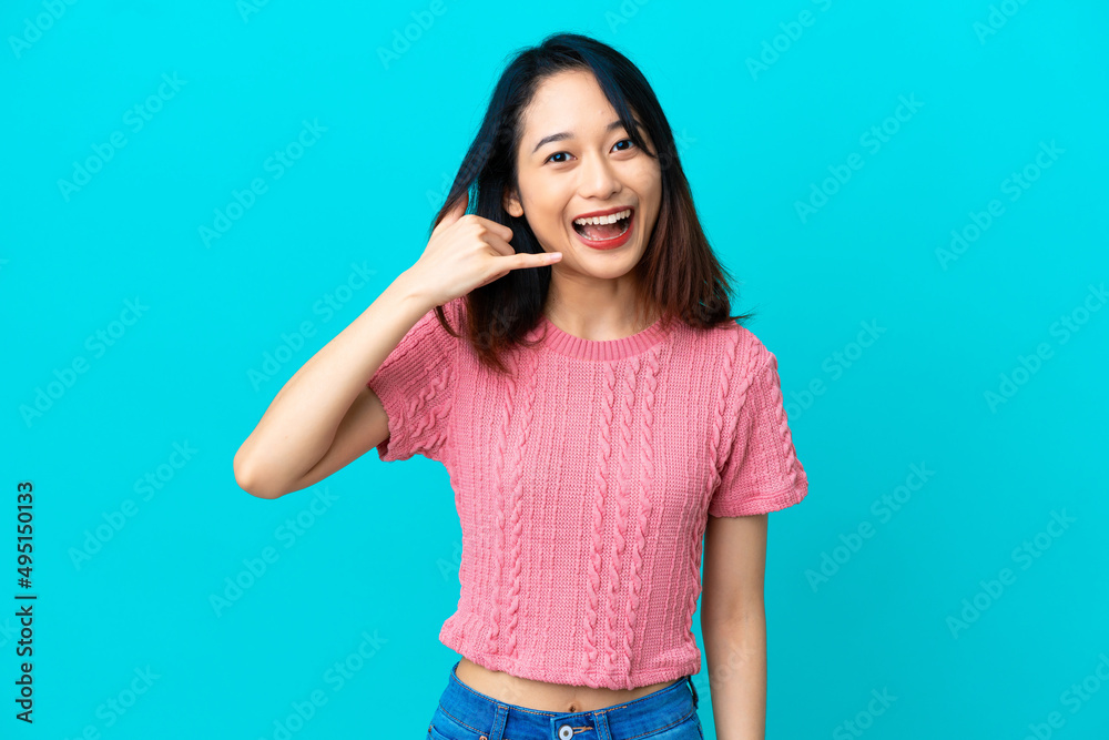 Young Vietnamese woman isolated on blue background making phone gesture. Call me back sign