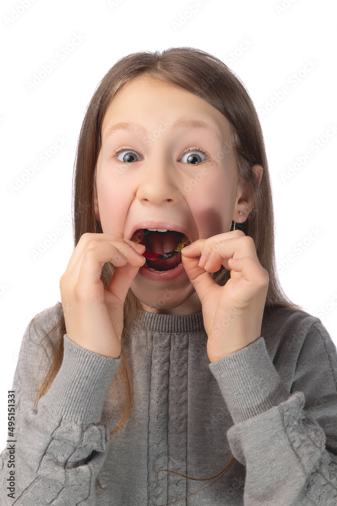 A cute little girl is putting on an orthodontic appliance. The concept of oral hygiene in childhood. Studio photo on a white background. A cute little girl is putting on an orthodontic appliance. The concept of oral hygiene in childhood. Studio photo on a white background.