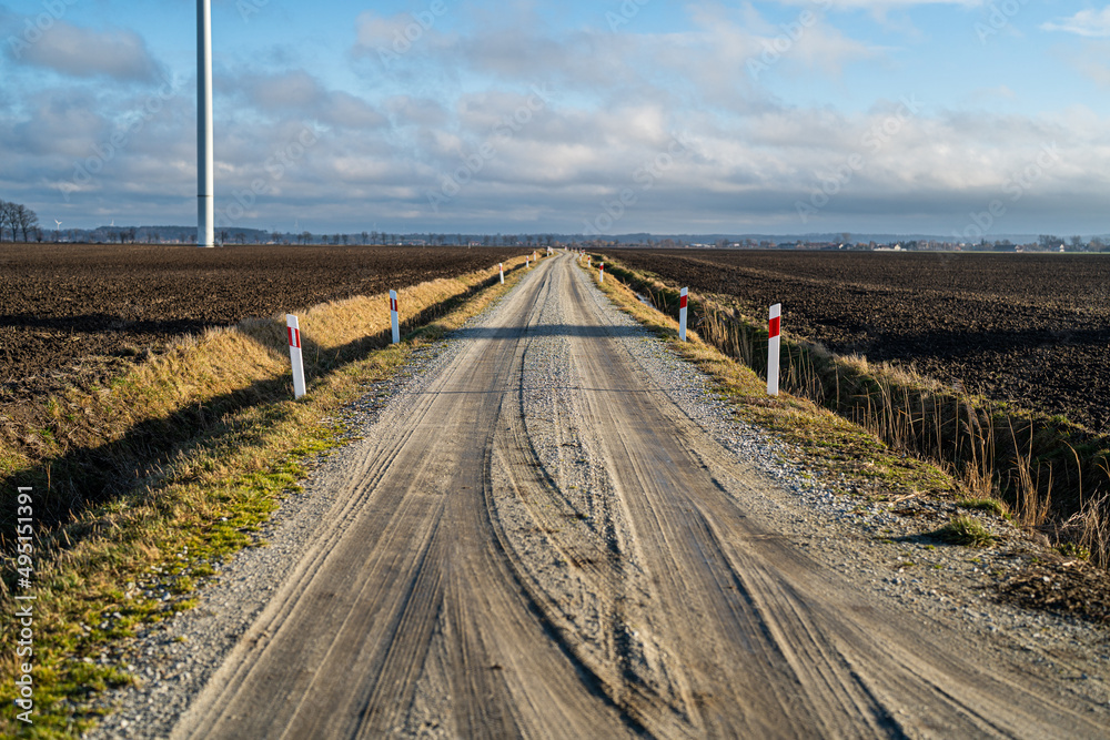 Fahrbahnmarkierungen - Feldweg im Hintergrund Windpark - Dorf