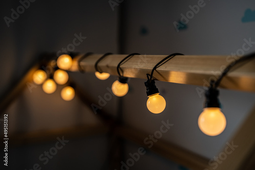 Obraz na płótnie lights - garland - children's room - warm light on a wooden house w salonie