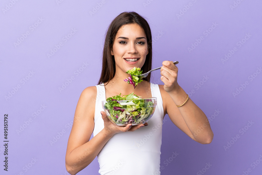 Young caucasian woman with salad isolated on purple background Young caucasian woman with salad isolated on purple background