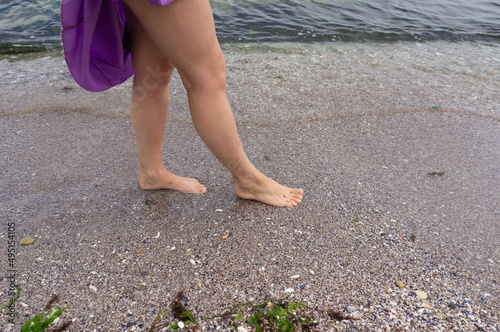 Girls feet on the pebbles. Walking near the surf line.