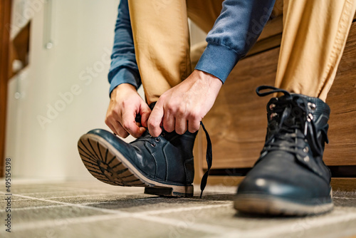 Close up of a man tying his laces on shoes at home.
